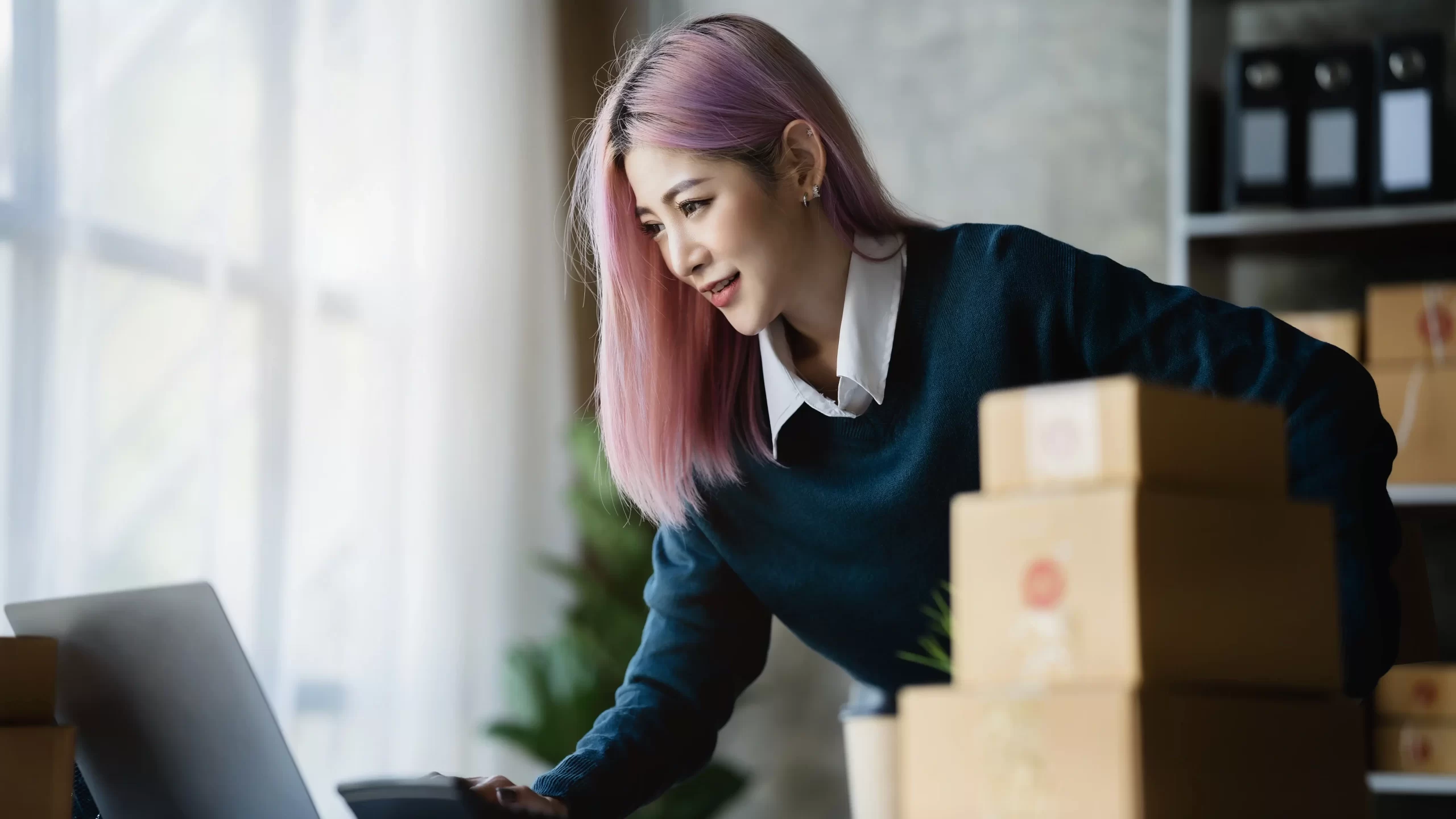 A girl looking at a laptop with boxes next to her